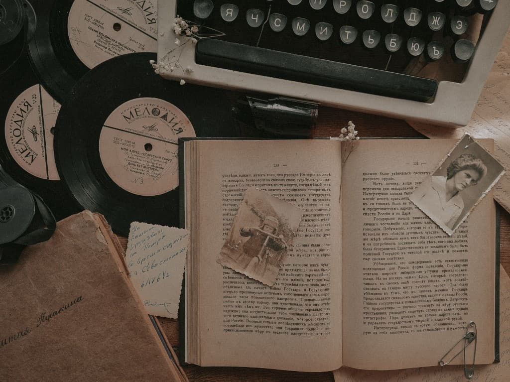 Vintage typewriter, open book, photographs and records arranged on a wooden table